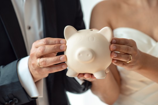 Bride and groom hold piggy bank.